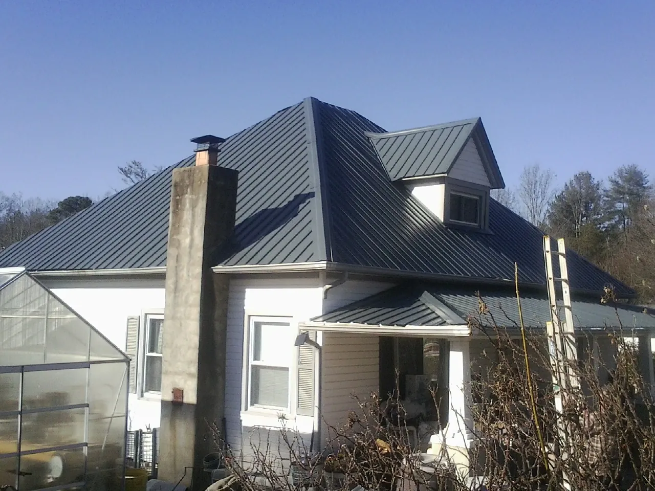 Dark blue standing seam metal roof on a white farmhouse with dormer — Slate & Tile Roof Repair by Roofing Brothers in Valdese