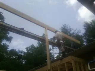 Carpenter setting a ridge beam over a new addition frame — Ice Dam Removal by Roofing Brothers in Valdese
