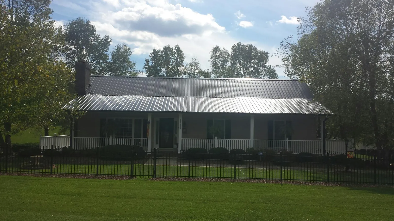 Gray metal roof on a brick ranch with a full width front porch — Gutter Guard Installation work by our crew in Valdese