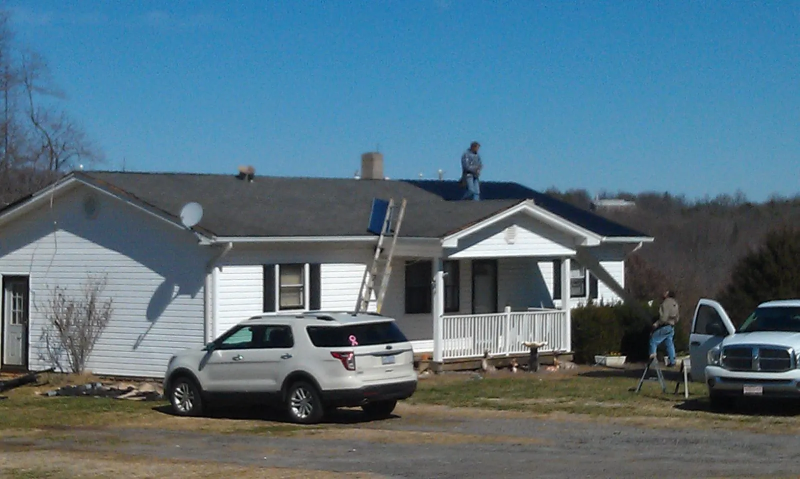 Roofers stripping shingles from a white ranch house roof in Valdese