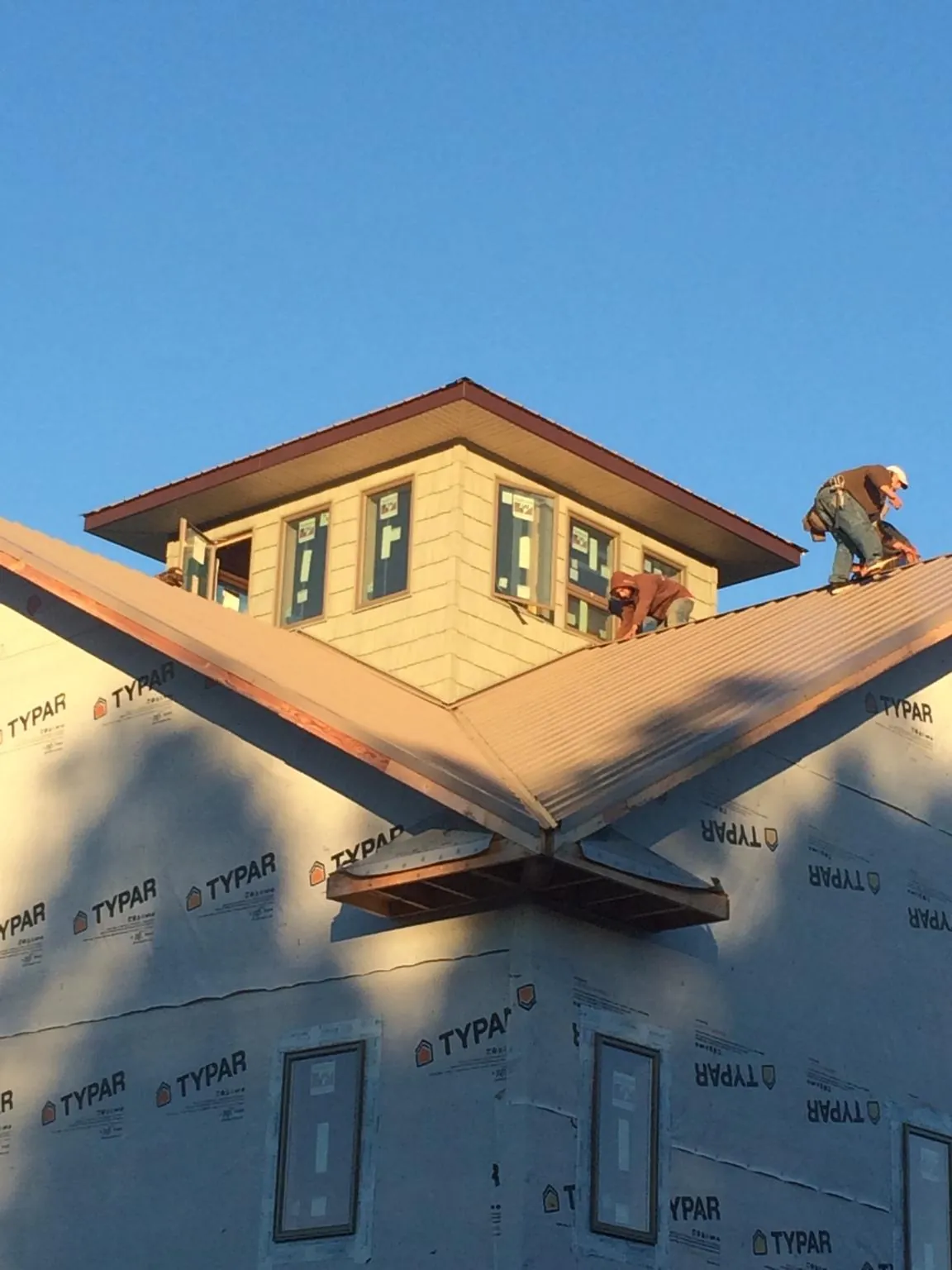 Roofers working around a rooftop cupola on a new metal roof at sunset — Roof Waterproofing in Valdese by Roofing Brothers
